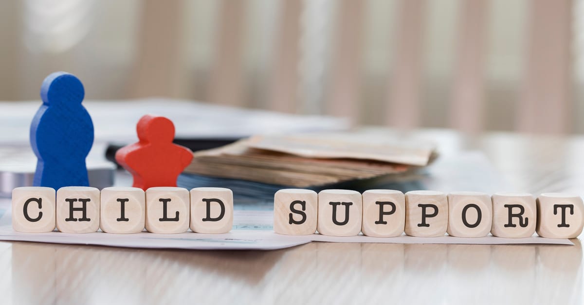 The words "child support" spelled out in wooden letter blocks, in front of blue and red people-shaped wooden blocks.