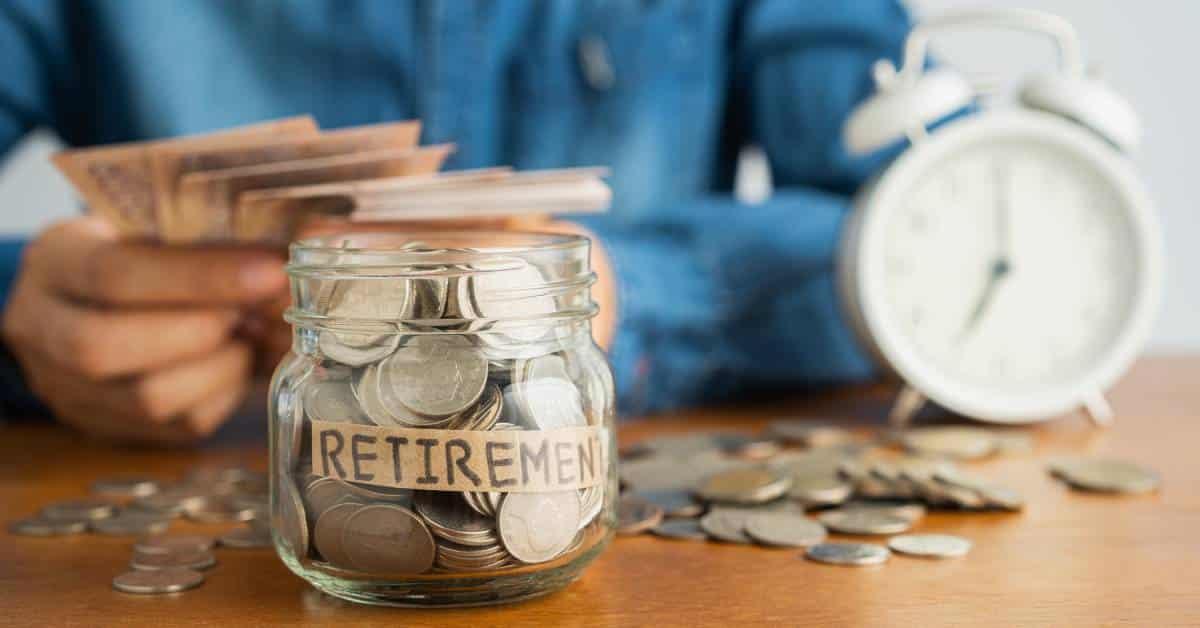 A glass jar labeled "retirement" and filled with coins. Loose change and an alarm clock sit behind it.