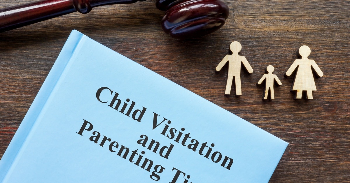 A book with "Child Visitation and Parenting Time" on its cover, on a desk next to a gavel and small models of people.