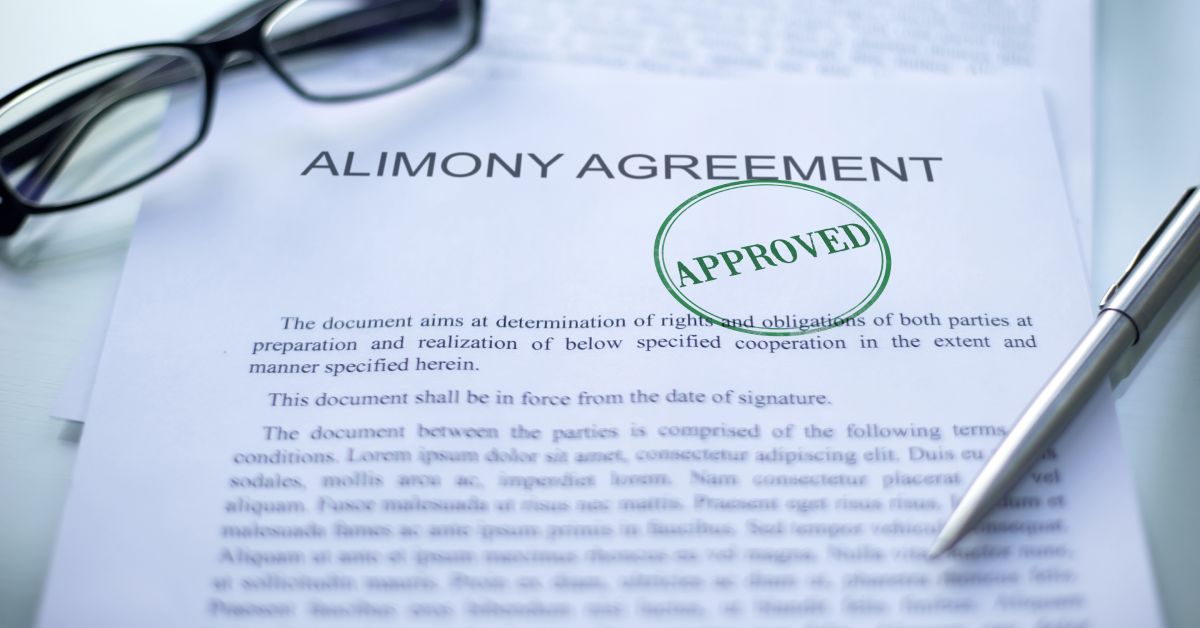 An alimony agreement marked with a green approval stamp lies on a desk beside eyeglasses and a pen.